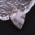 Detailed macro view of shield-shaped pink quartz pendant with gold-plated metal edging - White Crystal