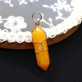 Detaillierte Nahaufnahme eines orangefarbenen Kristallanhängers mit silberner Drahtwicklung - 10x40mm / US 6