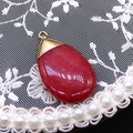 Detail view of teardrop red agate stone pendant with gold clasp on lace and pearl background - 20x35mm / Pink (Color 1)