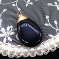 Detailed view of teardrop black stone pendant with golden clasp on lace texture - 20x35mm / Black Agate