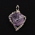 Makroaufnahme von Amethyst-Rohstein-Anhänger mit silberner Drahtwicklung auf schwarzem Samt - Amethyst
