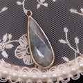Vue détaillée du pendentif en pierre naturelle facettée et monture dorée sur dentelle - Labradorite