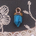 Dettaglio del ciondolo a colonna esagonale in pietra blu con cappuccio dorato su pizzo - 6x14mm / Turchese blu