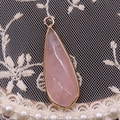 Détail d'un pendentif goutte en quartz rose facetté avec bordure en métal doré - Quartz rose