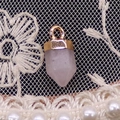 Dettaglio del ciondolo a colonna in cristallo rosa con cappuccio dorato su pizzo bianco - 6x14mm / Quarzo rosa