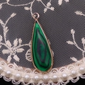 Pendentif goutte en malachite avec cadre doré sur un fond de dentelle élégant - Malachite