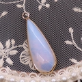 Pendentif goutte en opale élégant avec bordure dorée sur fond de dentelle blanche - Opale