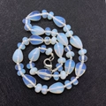 Macro detail of tear-drop opal beads with a silver lobster clasp on black background - Opal