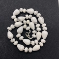 Macro shot of white turquoise teardrop and disc beads with a silver lobster clasp - Howlite