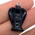 Piccolo ciondolo a forma di angelo in pietra nera con gancio in argento mostrato a mano - Forma di angelo / Agata nera