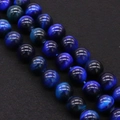 Macro shot of polished blue tiger eye beads with natural cat-eye effect on black texture - Indigo Blue (No.5)