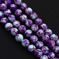Makroaufnahme von lila und hellblauen Natursteinperlen mit Marmortextur auf schwarzem Grund - 4mm / US 4