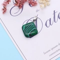 Macro detail of malachite textured square pendant with silver clasp on a gift card - Malachite