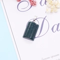Macro detail of green aventurine cylinder pendant with silver bail on artistic paper - No.5 Dark Green Stone