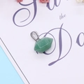 Macro shot of a faceted green natural stone pendant with a silver metal clasp - Green Aventurine