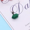 Green malachite hexagonal prism pendant with silver clasp on decorative background - Malachite