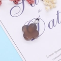 Clover-shaped translucent brown agate pendant with silver bail on a decorative floral base - Grey Agate
