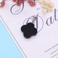 Polished black onyx four-leaf clover pendant with silver clasp on decorative background - Black Agate