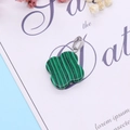 Malachite clover pendant with green stripes and silver clasp on a decorative background - Malachite