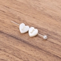 Détail de perles en nacre en forme de cœur avec gravure dorée de la lettre J pour bijoux - Lettre J