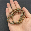 Hand hält bunte 2x4mm Naturstein-Zylinderperlen für die DIY Schmuckherstellung - 2x4mm / Picasso Jaspis