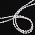 Macro shot of white teardrop shell beads with iridescent luster on a dark background - 4x7mm / White Shell