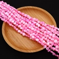 Detailed view of irregular pink shell beads with natural luster on a wooden plate - 4-6mm, 27g / Pink (Color 1)