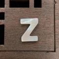 Natural white mother of pearl letter Z bead with iridescent finish on wooden surface - Letter Z / 12mm