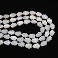 Macro detail of white mother of pearl Hamsa hand beads for DIY jewelry making with luster - Small Hand Shape / 10x15mm