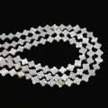 Macro detail of white natural shell beads in a clover shape with pearlescent finish - Four Petal Flower