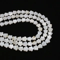 Macro detail of natural white mop shell flower beads with shimmering pearlescent luster - Five-Petal Flower