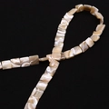 Macro shot of square natural sea shell beads with pearlescent luster on a black surface - 8x8mm 22g / Nude