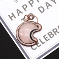 Macro view of rose quartz crescent moon pendant with vintage copper metal frame - 4.3cm x 5.5cm / Rose Quartz
