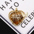 Macro shot of heart-shaped tiger eye stone pendant with wire-wrapped gold butterfly detail - 42x43mm / Tiger's Eye