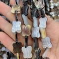 Macro shot of butterfly-shaped natural shell beads with iridescent luster for jewelry DIY - Butterfly / 10x15