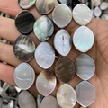 Hand holding natural mother of pearl oval shell beads with iridescent abalone finish - Marquise / 15x20