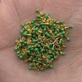 Golden DIY jewelry chain with green enamel beads held in palm for scale and detail - In Roll / Green