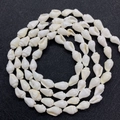 Makro-Detail von natürlichen elfenbeinweißen Spindelschalen-Perlen für DIY-Schmuck - Weiße Muschel Stil / 6-10mm / Weiß