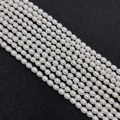 Strands of white rice-shaped freshwater pearls with natural luster on black background - 2-3mm / White