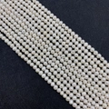 Strands of premium cream-white freshwater pearls with natural pink luster on black background - AA Grade / 2-3mm