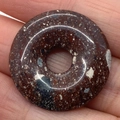 Red brecciated jasper donut pendant with natural stone patterns held in hand - Red-Brown Spotted Stone (No. 15)