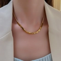 Gold square cube pendant snake chain necklace worn by a woman in a white blazer suit - Necklace Style / Gold