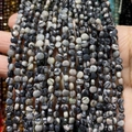 Makroaufnahme von facettierten 4mm Zebrastein-Perlen mit natürlichem Schwarz-Grau-Muster - 4mm 93 Stk./Strang 7g / Rhodonit mit schwarzen Linien