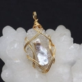 Macro detail of handmade gold wire wrapped natural pearl and crystal pendant on white stone - Gold Thread