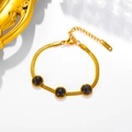 Close-up of gold stainless steel snake chain bracelet with three dark cat eye stones - Bracelet / Black
