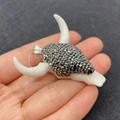 White bull skull pendant with inlaid dark stones and silver clasp held by hand - 45x46mm / White (No. 1)