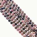 Dettaglio macro di perle in rodonite sfaccettata con trame naturali rosa e nere venate - Rodonite con linee nere