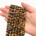 Faceted tiger eye stone beads in brown and yellow held in hand for jewelry making - 8mm / Tiger's Eye