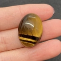 Handbeeld van een gepolijste ovale tijgeroogsteen 18x25mm met natuurlijke goudbruine strepen - Tijgeroog / 18x25mm