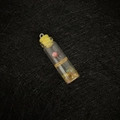 Miniature glass bottle pendant with pink dried flower and yellow cap on black background - Yellow
